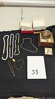 All jewelry items displayed on black cloth with empty boxes behind, white card with lot number 33 in front.