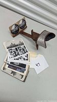 Photo showing the vintage 3D stereo-scope viewer and multiple black and white stereo image cards arranged on a surface.