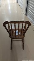 Rear view of a wooden rocking chair showing curved top rail and turned spindles.