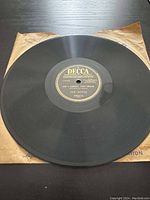 Top-down view of black Decca 78 RPM record resting on protective paper sleeve, showing full record and label center.