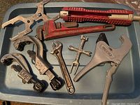 Full view of all plumbing tools laid on a tray including Ridgid cutters, faucet tool, valve key, and adjustable wrench.