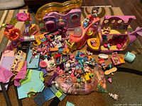 Wide view of lot showing large assortment of Littlest Pet Shop figures, accessories and two large playsets including a pink airplane toy and other pink and purple themed pieces.