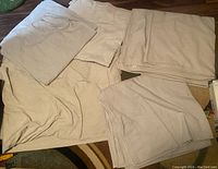 Five folded large canvas drop cloths laid out on floor, showing condition and color.