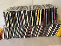 Two rows of music CDs stacked horizontally showing front spines and cases in mostly good condition.