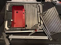 Husky tile saw base with cutting platform, ruler, metal plate and handle piece visible