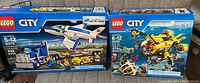 Front view of both Lego City boxed sets showing Deep Sea Submarine and Training Jet & Transporter with piece counts and set numbers