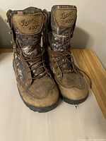 Front view of the pair of Danner Pronghorn boots showing mossy oak camo pattern and brown leather with laces tied.