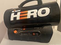 Side view showing brand name, control knob, and information labels on black cylindrical heater.