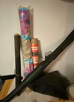 Photo showing rolls of black window mesh fabric, burlap roll in original packaging, and roll of wire mesh tied together.