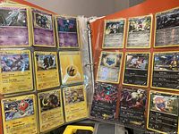 Open binder showing clear plastic sheets with multiple Pokémon cards in rows, including Electric and Psychic types.