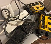 Five power bars from various brands arranged on a surface, showing use and cords tangled together.