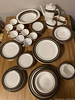 Top-down view of entire set arranged on table, showing plates, bowls, cups, teapot, and serving items with distinctive trim.