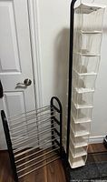 4-shelf black plastic shoe rack with metal rods standing assembled next to a wall, also showing the beige fabric over-the-door shoe organizer hanging on a wall hook.