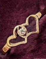 Close-up photo showing detailed front view of the 10K gold ring with two linked open heart shapes and a small central diamond.