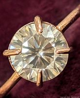 Close-up photo of the 2ct round moissanite gemstone set in 14K gold with four prongs, showing facets and sparkle.