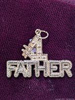 Front view of the gold #1 Father pendant on dark fabric background.