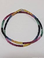 Full view of the colorful faceted sapphire and emerald beaded necklace laid out in a circle.