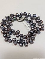 Full view of the pearl necklace showing the peacock-colored fresh water pearls strung together.