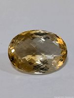 Clear image of faceted oval citrine gemstone on white background showing the checkerboard cut and internal clarity