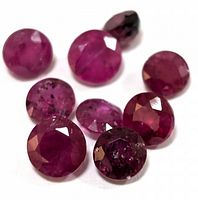 Close up of the 8 loose round cut rubies showing facets and color variations.