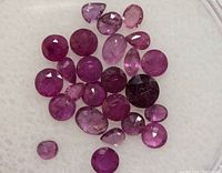 Alternative close-up photo showing the collection of faceted genuine rubies on a white background to highlight color and inclusions.