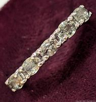 Close-up image of sterling silver ring with multiple oval-cut natural green sapphire gemstones in continuous prong setting.