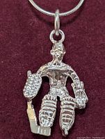 Close-up photo of the sterling silver hockey goalie pendant necklace on burgundy fabric background