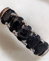 Close-up photo of sterling silver ring featuring five black sapphire stones set in prongs.
