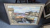 Framed watercolour painting showing detailed harbour scene with boats, docks, houses, rocks, sky, and reflections in water.