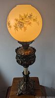 Full view of antique Bradley & Hubbard Art Nouveau table lamp with floral hand-painted glass shade on ornate metal base