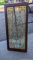 Full frontal view of the stained glass panel showing the Gothic design in yellow and clear textured glass with wooden frame.