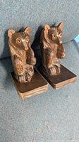 Front angled view of pair of hand carved wooden bear bookends showing intact glass eyes and base.