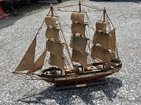 Full view of the wooden ship model showing three masts, rigged sails, and the hull.