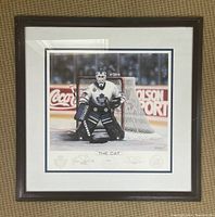 Framed art print showing Toronto Maple Leafs goalie in playing stance in front of net with arena logos visible behind him.