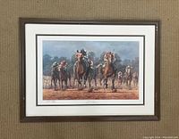 Framed print showing a horse race with prominent figures Alysheba and Bet Twice in the lead, resting against a carpet background.