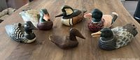 Lot of six handcrafted wooden duck decoys displayed on a table, showing variety of species and paint details.