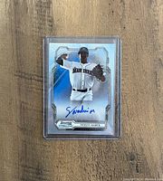 Noelvi Marte Bowman Sterling autographed rookie card in protective sleeve on wooden background.