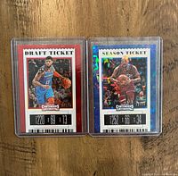 Photo of two Panini Contenders Draft Ticket basketball cards in protective cases showing Paul George and Charles Barkley in action. The Paul George card has a red border and is serial numbered 220/699. The Charles Barkley card has a blue holographic border and is serial numbered 252/299.