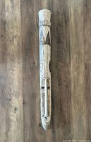 Tall, narrow handcrafted wooden mask from Ghana with elongated facial features and decorative carvings.