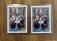 Front of two 1992-93 Topps Shaquille O'Neal Orlando Magic rookie cards in plastic sleeves laid on wood surface