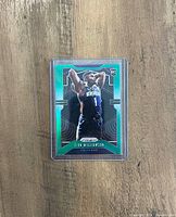 Zion Williamson rookie basketball card with green metallic border in a protective hard plastic case, placed on a wooden surface.