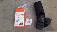 Canon Speedlite 430-EX flash unit in its black soft case and j5create USB-C to 4K HDMI cable in orange/white packaging placed on floor.