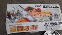 Box of mandoline slicer showing branding, usage suggestions, and images of sliced vegetables.