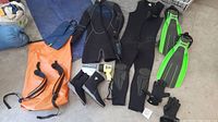 Photo showing two scuba wet suits, dry bag, flippers, gloves, and boots laid out for condition and content verification