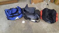 Overview photo showing all three duffle bags (Adidas, Nike, Under Armour) laid out on a concrete floor.