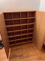 Front view of cabinet with both doors open, showing multiple divided shelves inside for CD storage.