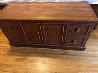 Front view of wooden cedar chest with five drawers and two-door cabinet in the center, showing dark wood finish and drawer knobs.