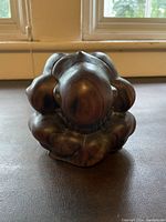 Front angled view of vintage solid wood Buddha sculpture showing bowing posture and wood grain details