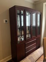 Front and side angle photo of the Arrese Brothers oak wood china cabinet with glass doors and drawers, showing the cabinet's overall condition and details.