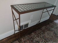 Front view of the Bombay Company console table showing metal frame and glass grid top.